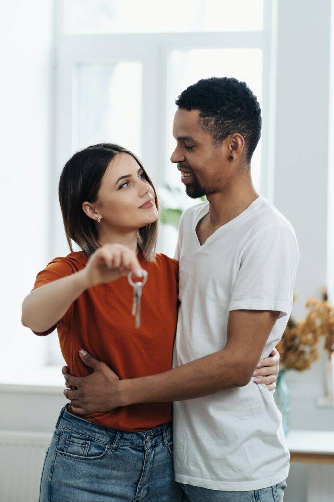 Happy young couple holding new house key indoors